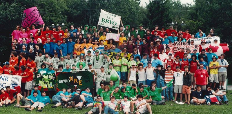 A diverse crowd of people celebrating at a concert, raising their hands and cheering.