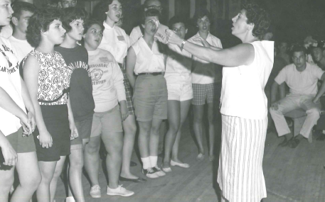 A diverse crowd of people celebrating at a concert, raising their hands and cheering.